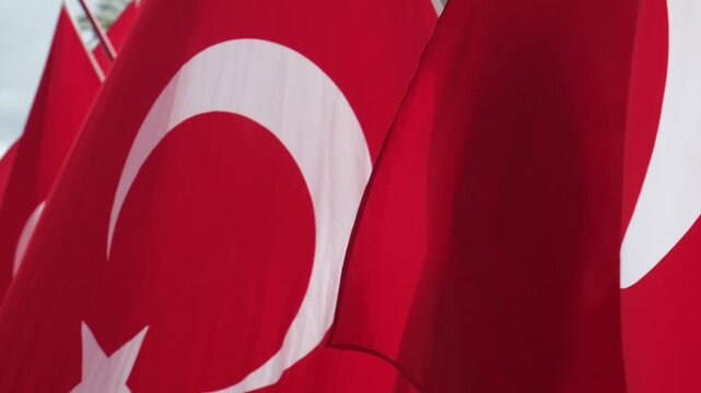 Close up video of a red Turkish flag with white crescent moon and star fluttering and waving gracefully in strong wind.