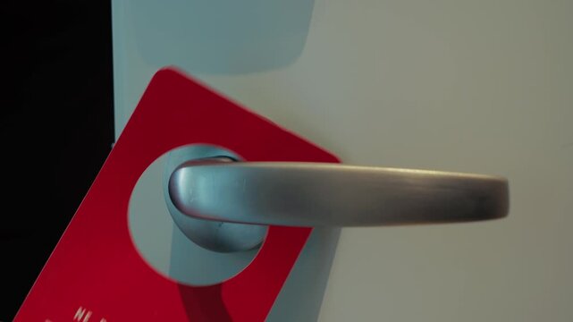 A close-up of a hotel guest hanging a sign on the doorknob requesting room cleaning or a do-not-disturb request. Concepts of hotel service, privacy, room cleaning, and hospitality in a modern hotel