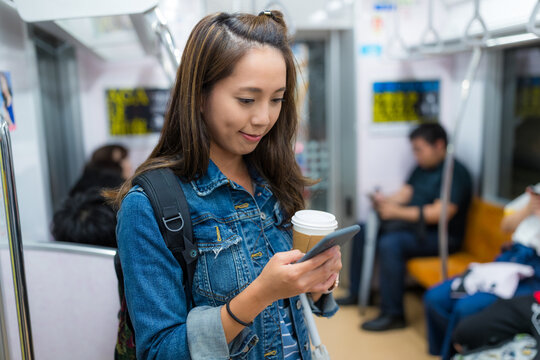 Travel woman holding coffee and using cellphone inside japan train compartment