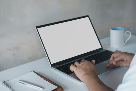 Professional remote work setup with blank laptop screen mockup, business man working from home desk with notebook and coffee, clean minimal workspace for productivity, digital lifestyle concept