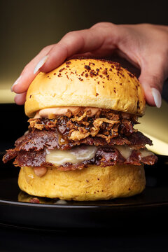 Close-up of a gourmet beef burger with toppings in realistic food photo style on dark background, concept of tasty comfort food