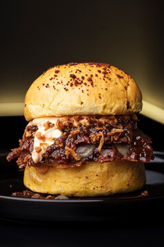 Close-up of a loaded burger with sauce and crispy layers in a realistic style on dark background, concept of gourmet comfort food
