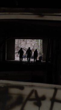 Group of three soldiers with rifles moving through dark building.