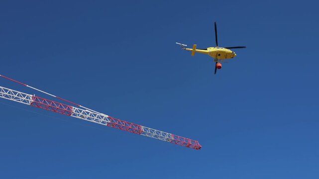 Firefighting helicopter dropping water on forest fire near residential area, Spain