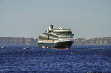 Luxury cruiseship cruise ship liner Eurodam anchoring at sea on sunny summer day during Mediterranean Greek Island Santorini caldera cruising with shore and rocky island in background © Tamme Wichmann