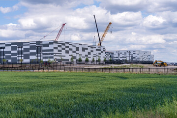 Exterior shot of a new data center building in Hutto, Texas with cranes visible on a partly cloudy day. © steheap