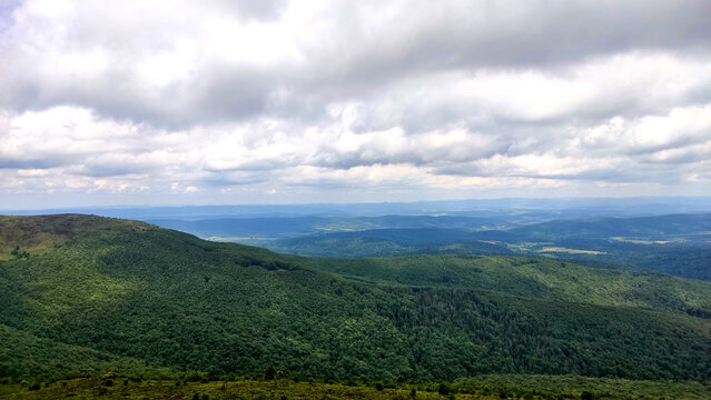 Remote mountain ridges and deep forest valleys under a cloudy sky in Bieszczady National Park