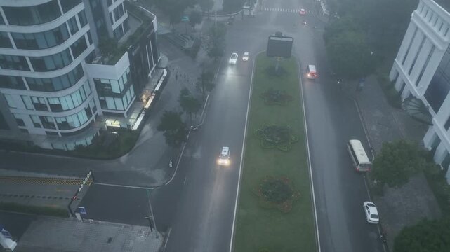 Central green median along Minh Khai street emerges through thick fog as vehicles pass slowly in subdued early morning urban scene.