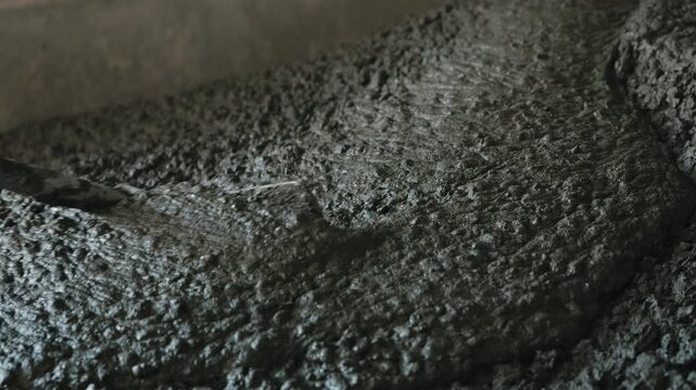 Leveling wet concrete surface with hand tool during floor work close up