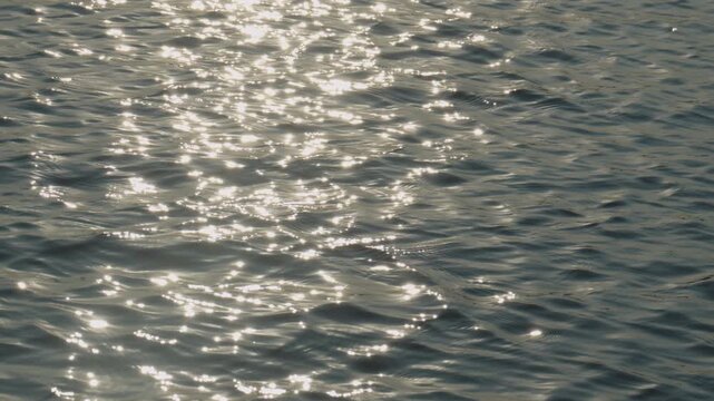 Slow motion sea waves glistening under warm sunlight with dreamy reflections and tranquil feeling