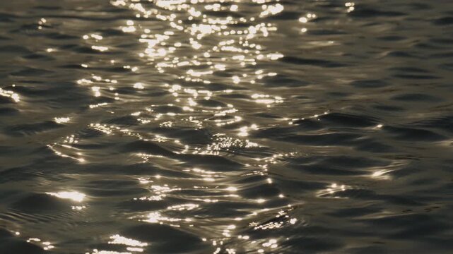 Slow motion sunlight reflecting on gentle ocean waves creating sparkling highlights and calm relaxing atmosphere