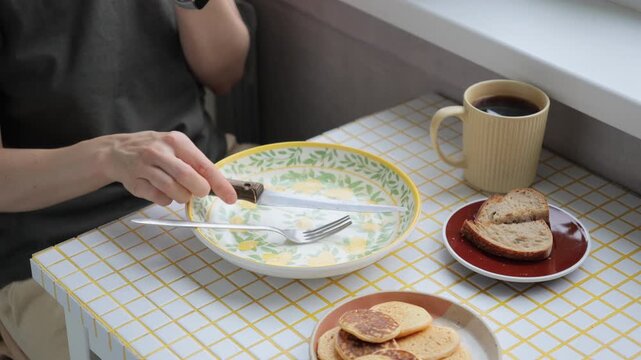 person finishes their breakfast or lunch in kitchen. delicious and healthy food cooked at home. woman eats flatbread pancakes and drinks coffee. vegetarian diet for body health. high quality 4k video