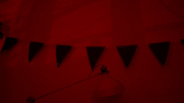 Crimson shadow ambiance. Shadowy crimson hue bathes festive quiet space. Moody deep red shadow drapes over empty celebration zone during peaceful nighttime atmosphere