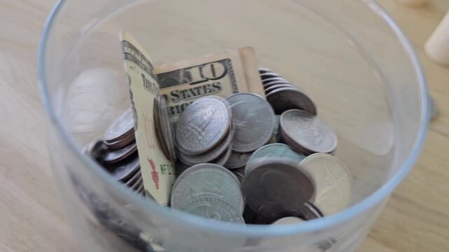 Jar filled with coins and cash in a bowl on a table showing different denominations of money found in America