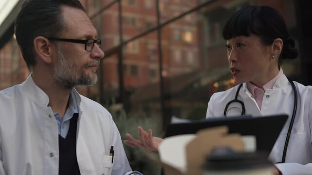 Two doctors discussing patient case during lunch break
