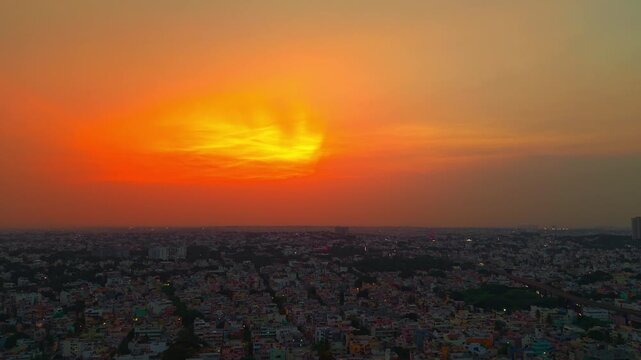Cinematic close-up of a vibrant orange and yellow sunset sky with silhouetted clouds.