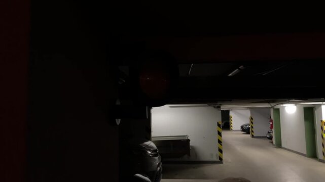 Underground parking garage warning light signaling sensor near entrance, dim concrete pillars, empty carpark lane, amber lamp casting shadow, industrial atmosphere