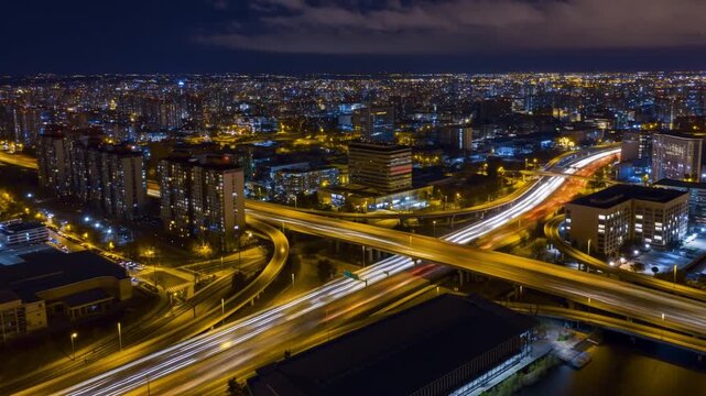 A modern metropolitan city at night, aerial view of illuminated skyscrapers and highway traffic
