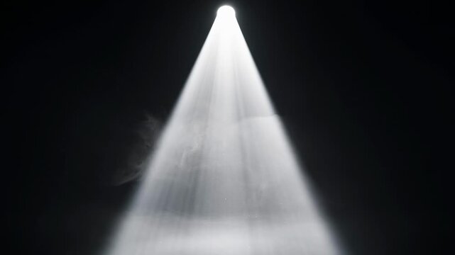 Bright white conical spotlight beam piercing through thick swirling smoke and mist against a dark background, creating dramatic atmospheric effect.