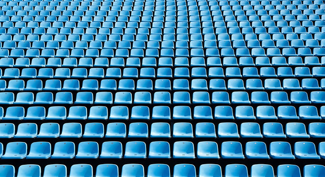 Abstract background of many rows of empty blue plastic stadium seats in a large outdoor arena with stadium seat
