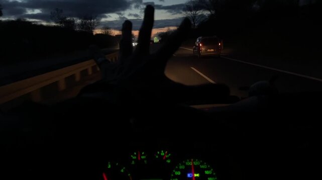 Twilight highway drive with sunset horizon, open road and guardrail, reflective asphalt, oncoming headlights, cab dashboard glow, hands on wheel, steady cruise, scenic longhaul