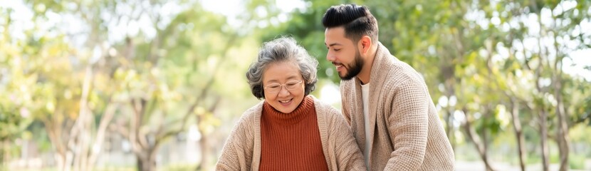 Fototapeta premium Young man assisting elderly woman walking in park