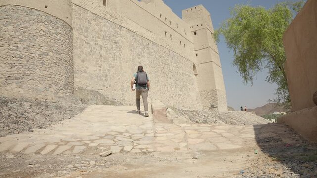 Static Shot of Tourist at Bahla Fort Exterior, Cinematic Male Traveler by UNESCO Heritage Mud-Brick Walls