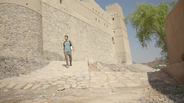 Static Shot of Tourist at Bahla Fort Exterior, Cinematic Male Traveler by UNESCO Heritage Mud-Brick Walls