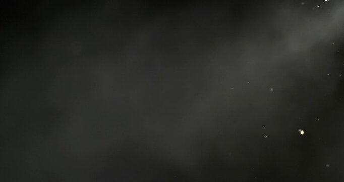 Super slow motion (1000 fps) vapor and fine droplets dispersing in air on black background. Misty fluid particles with soft light, evoking evaporation, diffusion and abstract motion.