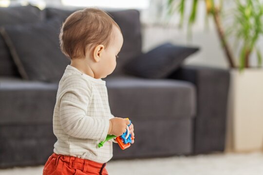 Toddler holding shape sorter toys standing at home, early development