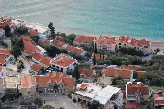 Scenic aerial view of Sveti Stefan, Montenegro, featuring traditional red-roof houses, coastal streets, and the clear turquoise Adriatic Sea.
