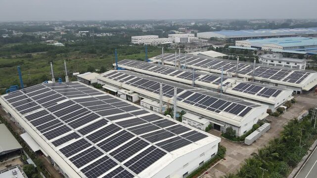 Aerial view of industrial factory buildings with solar panels installed on roofs under a hazy sky in An Phuoc, Dong Nai, Vietnam.