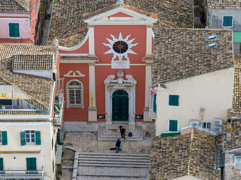 Aerial view of the Metropolitan Cathedral of Panagia Spilaiotissa and Saint Theodora in Corfu Old Town, Greece, featuring historic red Venetian architecture, terracotta rooftops