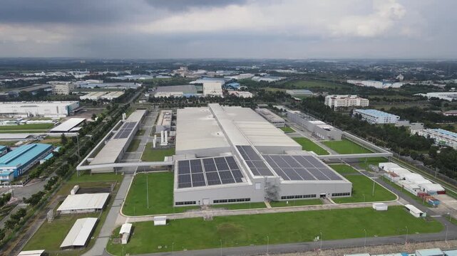 Aerial view of a modern industrial factory featuring solar panels on the roof and green lawns in an industrial park in An Phuoc, Dong Nai, Vietnam.