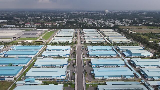 Aerial view of rows of blue-roofed industrial warehouses and manufacturing facilities separated by a central road in An Phuoc, Dong Nai, Vietnam.