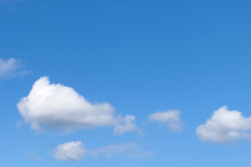 Blue sky with scattered white clouds. Soft cloud formations drift across a clear atmosphere. Natural weather background for travel, design, and outdoor themes.. © valiantsin