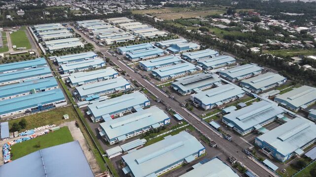 Aerial view of a large industrial park with blue-roofed warehouses and factory buildings surrounded by greenery in An Phuoc, Dong Nai, Vietnam.