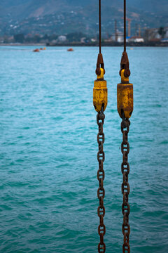Rusty Industrial Crane Chains Over Blue Sea