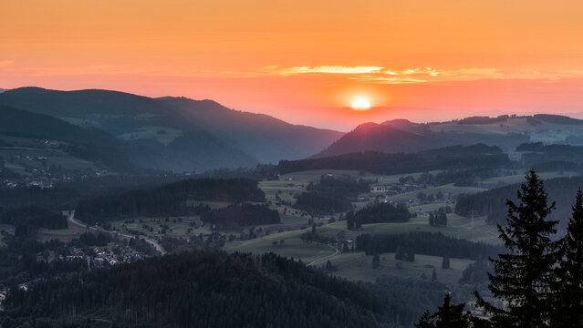 Atmosph&auml;rische Landschaft im Schwarzwald bei Sonnenuntergang. Die tief stehende Sonne taucht die sanften H&uuml;gel und T&auml;ler in warmes Licht, w&auml;hrend sich die Landschaft in weichen Farbverl&auml;ufen und ruhig
