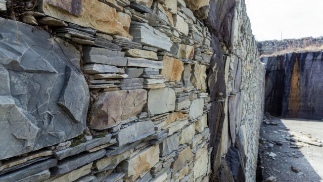 Textured stone wall construction with layered slate and rough-hewn rock faces