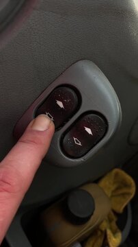 Switching window with touch. Closeup of door panel with textured trim during switch press. Detailed view of finger activating window switch inside car door panel