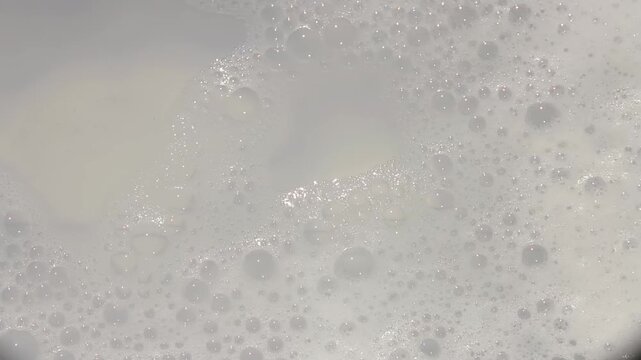 Bubbles forming and shimmering in warm, soapy water during a relaxing bath at home