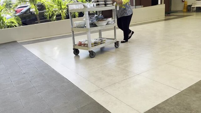 Kitchen Staff Pushing Service Trolley with Clean Dishes
