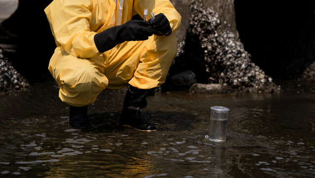 Environmental Scientist Collecting Water Samples for Safety Testing Near Industrial Plant