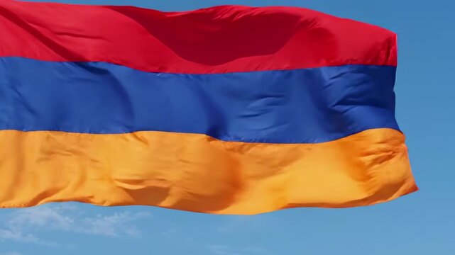 Armenia waves flag gently in the breeze. Sky shows soft clouds behind the flag. Symbol of national pride in motion. Perfect for patriotic or cultural themes
