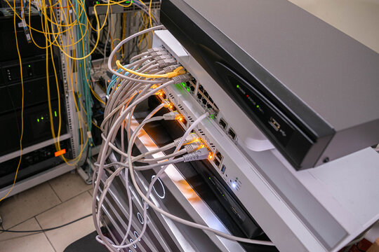 Close-up of network equipment with ethernet cables Connected to router and switch. Data center hardware, IT infrastructure and communication technology concept.