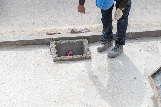 Construction worker measuring a manhole on a worksite The Concept of precision