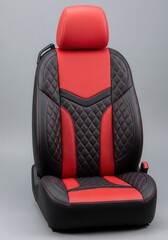 Fototapeta premium Modern automotive seat features red and black quilted leather upholstery against a neutral backdrop.