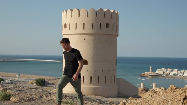 Slow Motion Male Tourist at Sur Lookout Tower, Cinematic Viewpoint Overlooking Coastal Oman City