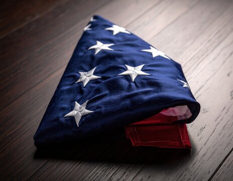 Meticulously folded American flag with embroidered white stars rests on a dark wooden floor symbolizing patriotism, honor, and remembrance for veterans and country